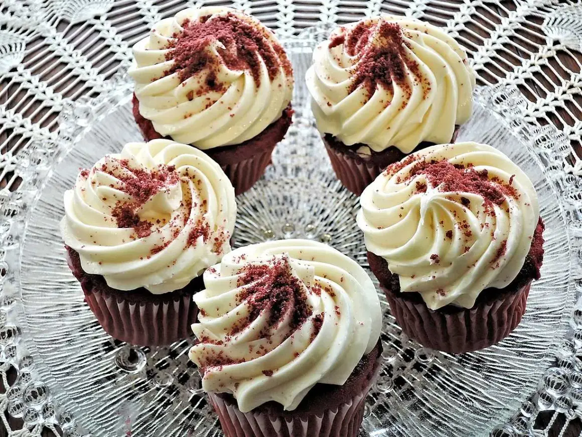 Fem röda sammetsmuffins med fluffig cream cheese frosting, strösslade med smulor.