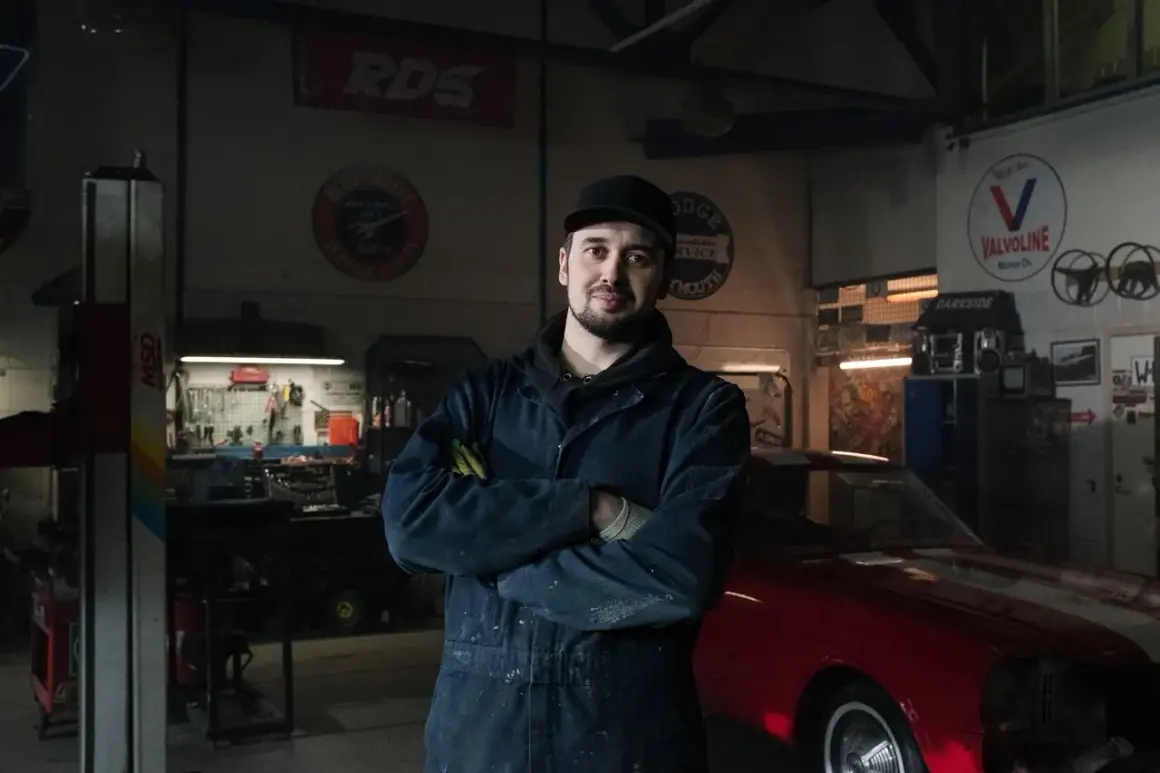 Mechanik w warsztacie z czerwonym autem. Co zrobić, gdy mechanik przetrzymuje auto? Zapytaj o fakturę i termin odbioru.