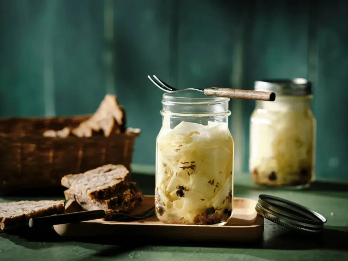 Kohlrabi fermentieren: Gläser mit eingelegtem Kohlrabi, Gewürzen und Brot im Hintergrund.