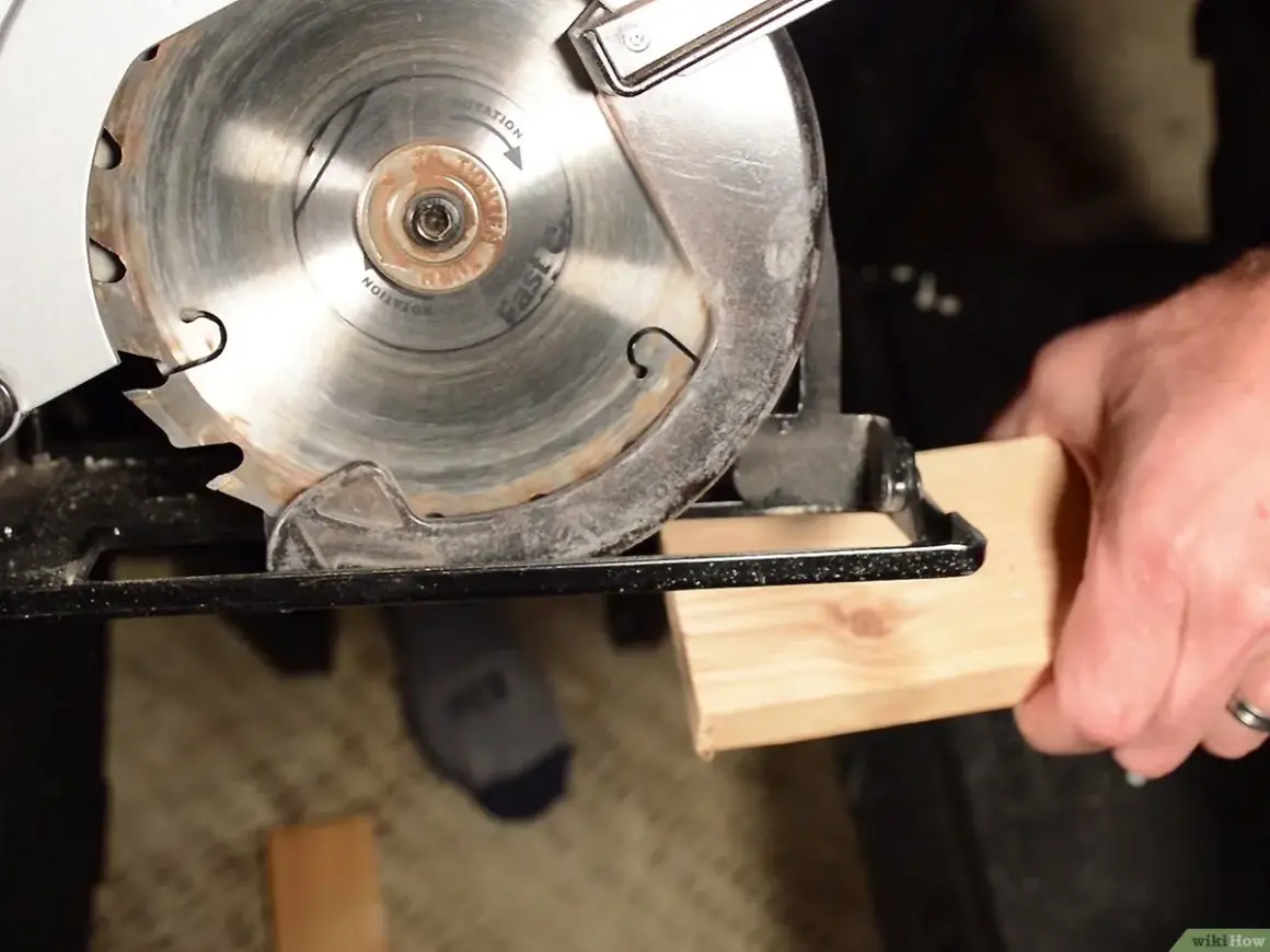 Démonstration de comment utiliser une scie circulaire pour couper du bois. La lame est prête à entamer le morceau de bois tenu par une main.