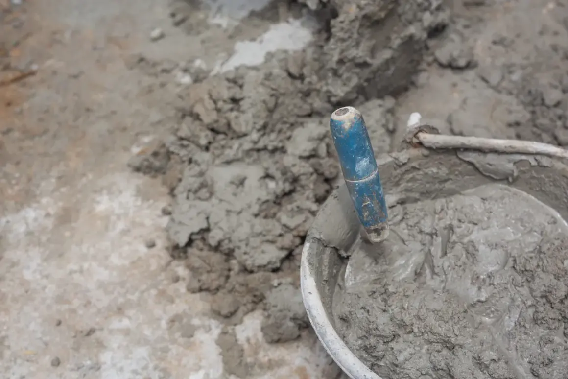 Paleta azul en un cubo con cemento fresco. El proceso de cómo hacer cemento es fundamental para la construcción.
