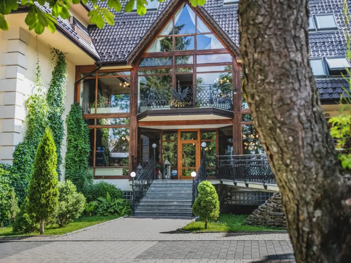 Elegancki hotel Belvedere z dużą, przeszkloną fasadą i zielenią wokół.