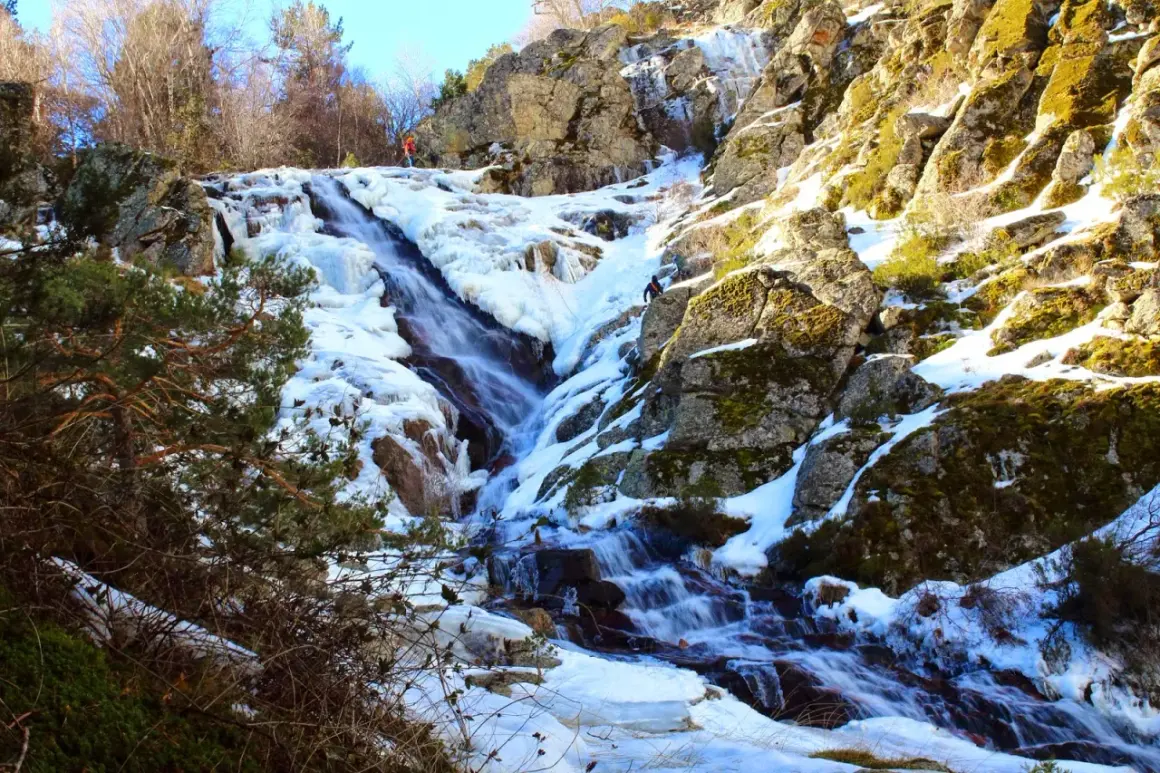 Cascada helada en el abedular de Canencia, con escaladores ascendiendo por el hielo y la roca.