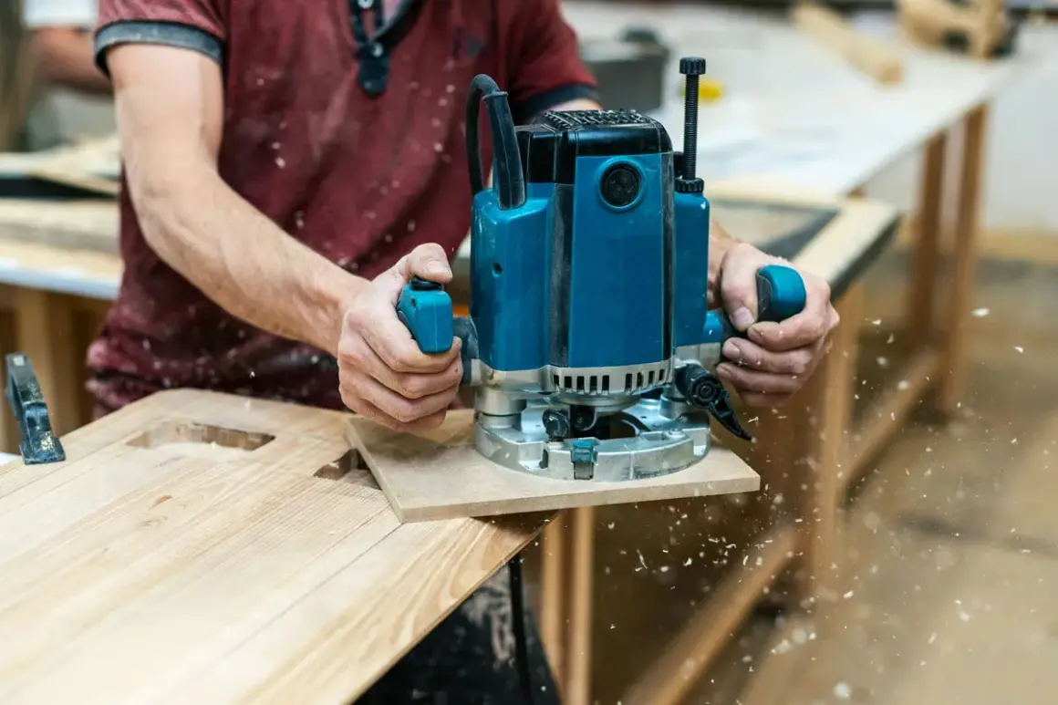 Un artisan utilise une défonceuse pour façonner du bois, créant des découpes précises. C'est une excellente démonstration de que faire avec une défonceuse pour des projets de menuiserie.