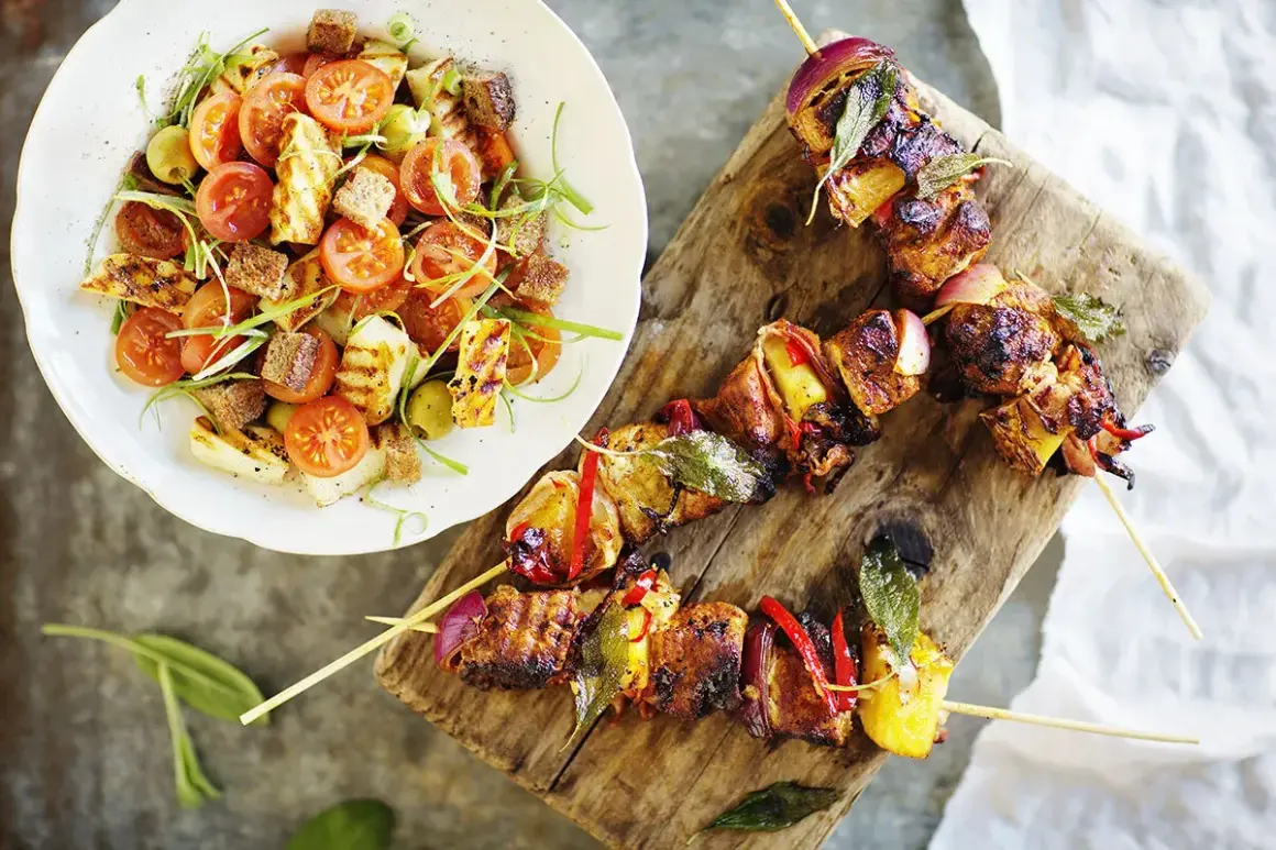 Grillspett med kött och grönsaker, serverade med en sallad på grillad halloumi, tomater och krutonger. Perfekt sommarmat recept för en härlig middag.