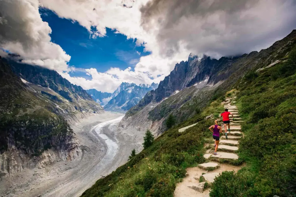 Deux coureurs sur un sentier de montagne escarpé, dominant un glacier spectaculaire. Le **top trail** offre une vue imprenable sur les Alpes.