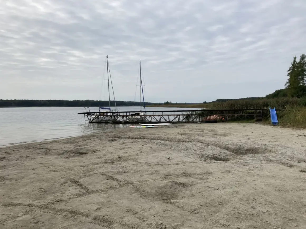Plaża nad jeziorem powidzkim z pomostem, dwoma żaglówkami i zjeżdżalnią. Idealne miejsce na wodne atrakcje.