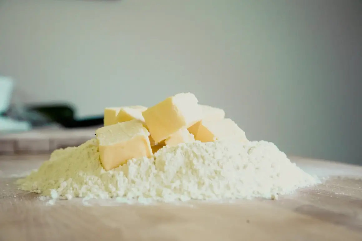 Kostki margaryny Kasi ułożone na kopczyku mąki, gotowe do pieczenia pysznych ciasteczek.