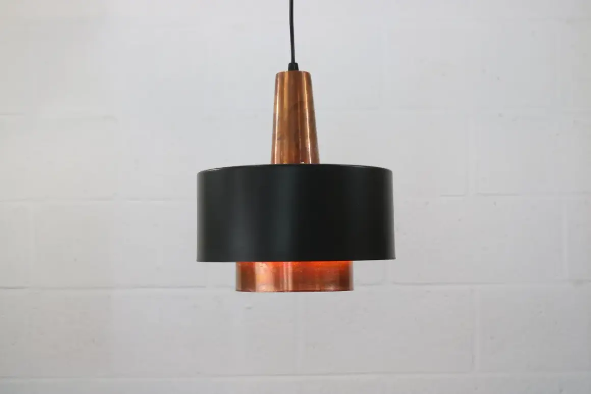 Stylowa lampa sufitowa z miedzi i czarnego metalu, dodająca ciepła wnętrzu.