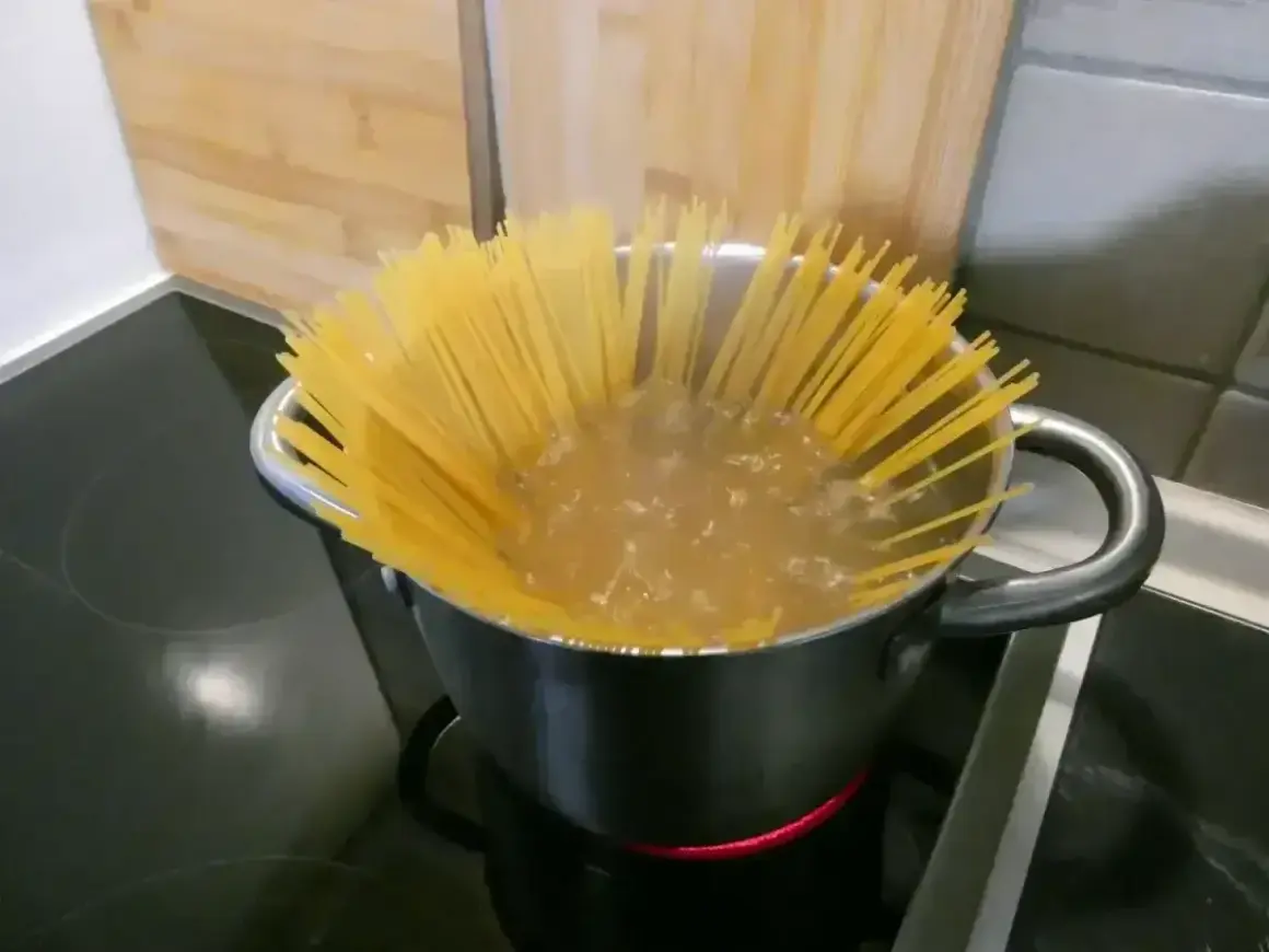 Długi makaron spaghetti gotuje się w garnku z wrzącą wodą. Czas gotowania jest kluczowy, by był idealnie al dente.