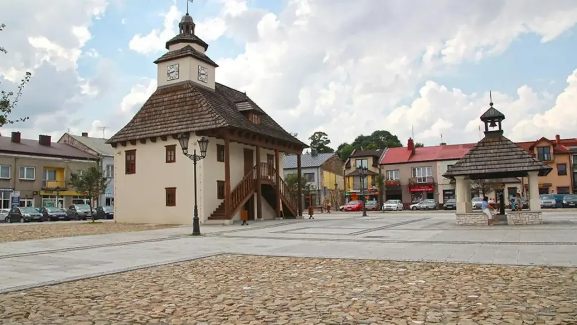 Rynek w Pilicy z ratuszem i studnią. Urokliwe miasto z brukowanym placem i kolorowymi kamienicami.
