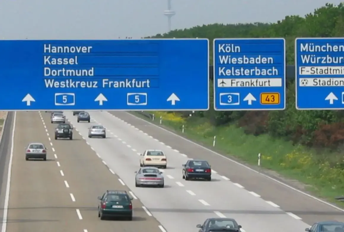 Niemiecki **autobahn** z niebieskimi tablicami kierunkowymi do Hanoweru, Kolonii i Monachium. Samochody jadą po wielopasmowej drodze.