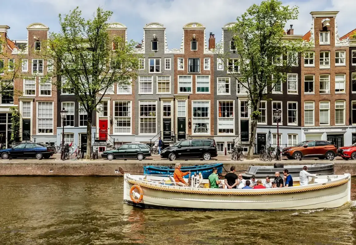 En båttur på kanalerna är ett måste i Amsterdam. Vackra hus och träd kantar vattnet.