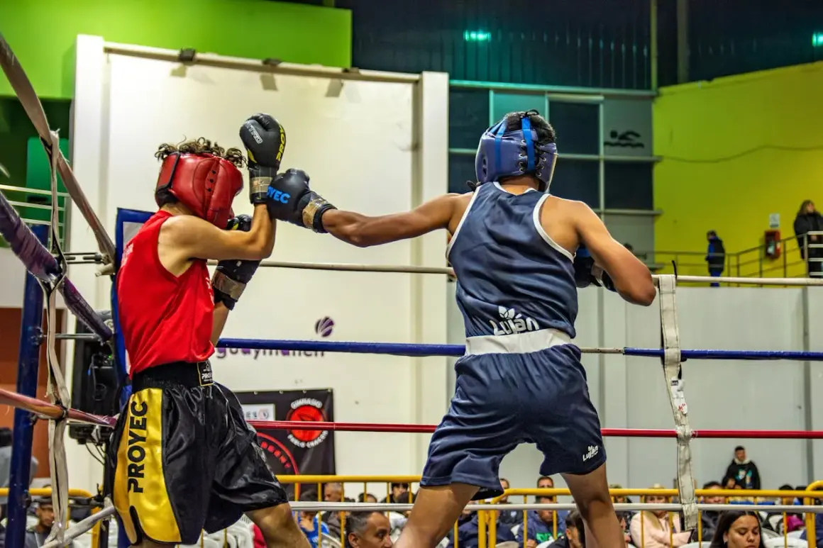 Two young boxers showcase their boxing skills in a ring, one in red, the other in blue, during a match.