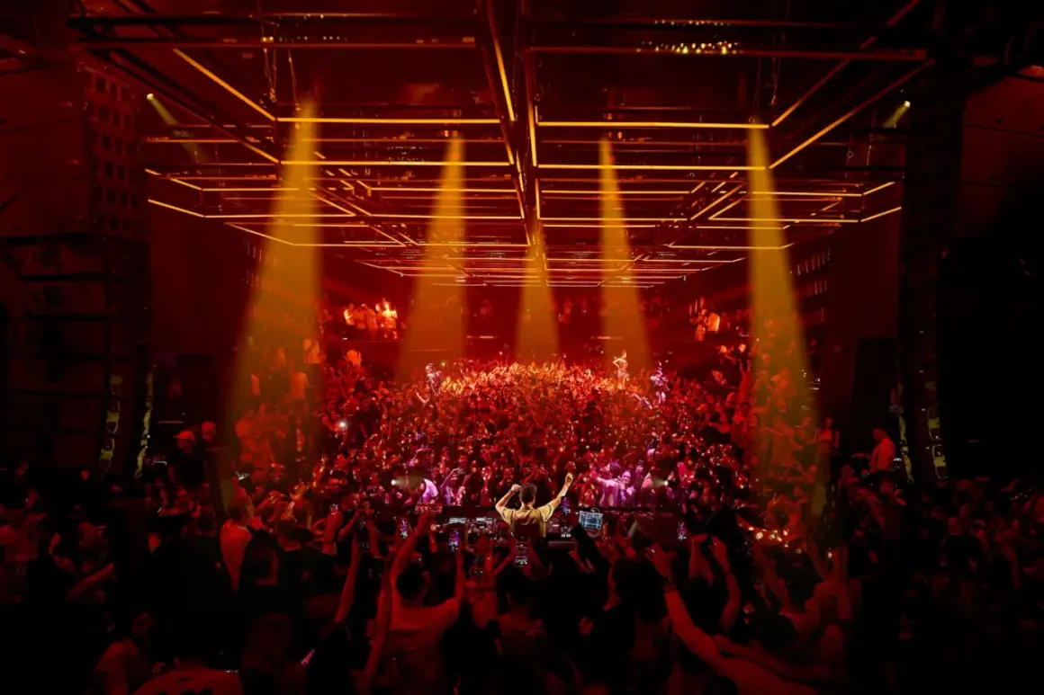 Folla in delirio per l'apertura discoteche Ibiza. Luci arancioni e DJ set infuocano la pista.