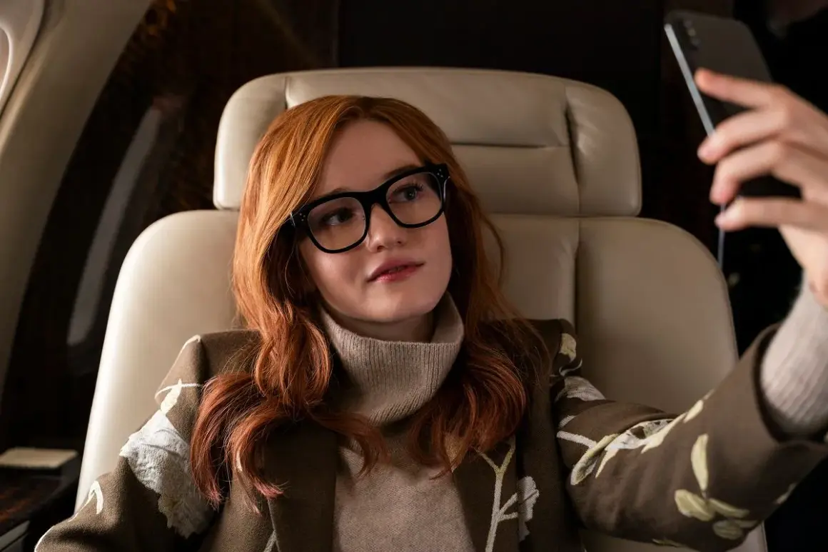 Anna Delvey, grana przez Julię Garner, w luksusowym wnętrzu samolotu, robiąc selfie.