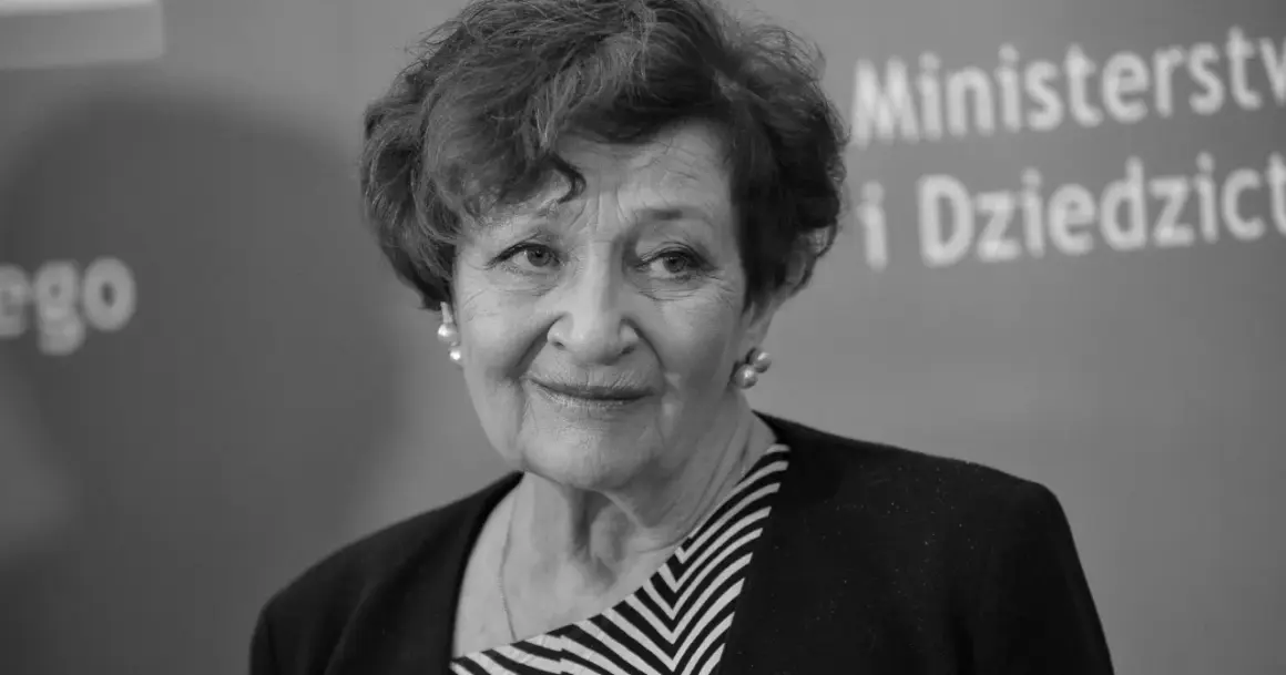 Uśmiechnięta Ewa Dałkowska, z perłami w uszach, na tle napisu "Ministerstwo i Dziedzictwo".