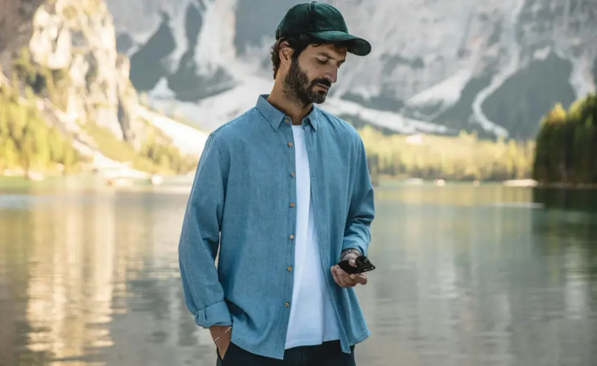 Un homme porte une chemise bleue décontractée, dont la matière légère est parfaite pour une journée au bord du lac.