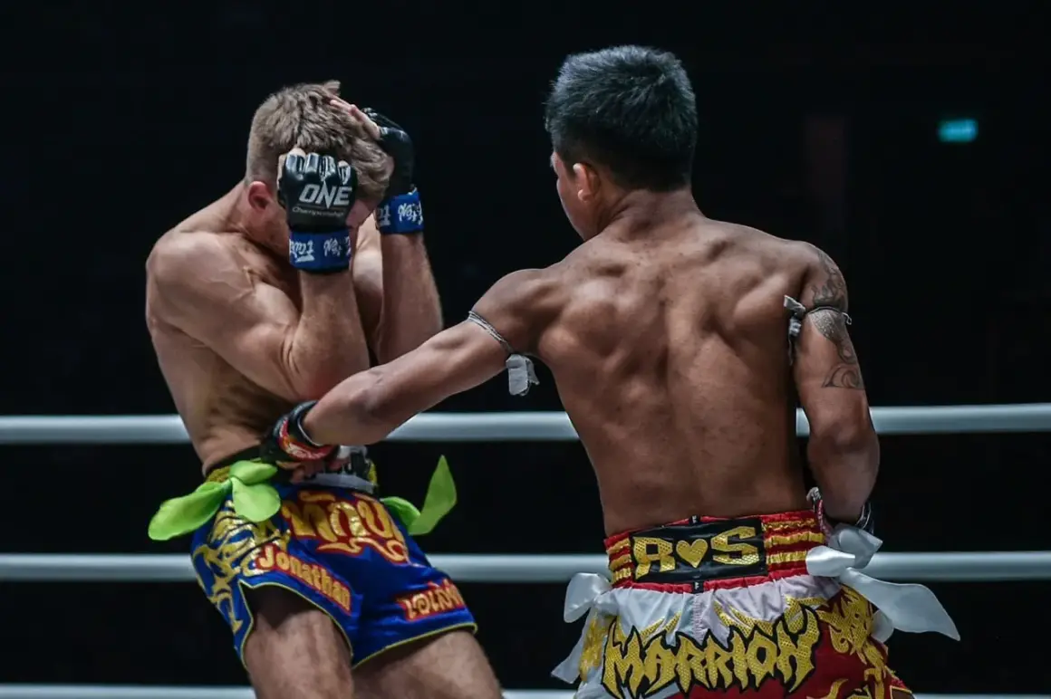 A Muay Thai fighter lands a powerful uppercut, connecting with his opponent's chin. The shovel hook defense is too late.
