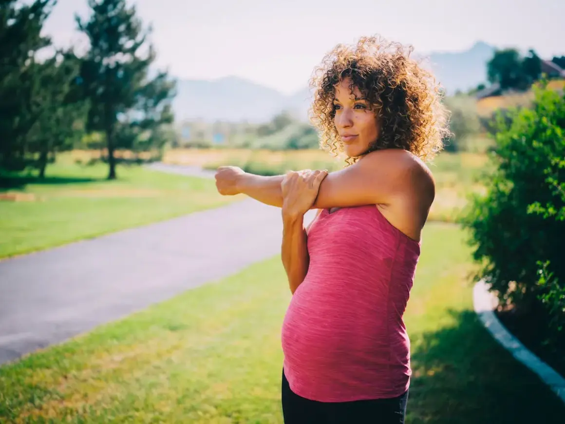 Femme enceinte s'étirant sur un sentier, se demandant si elle peut courir enceinte.