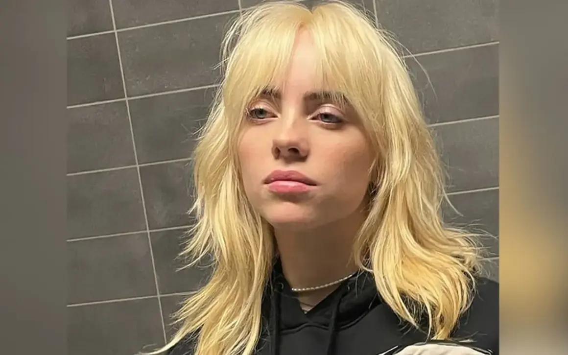Blond włosy w stylu wolf cut, z grzywką i warstwami, opadające na ramiona.