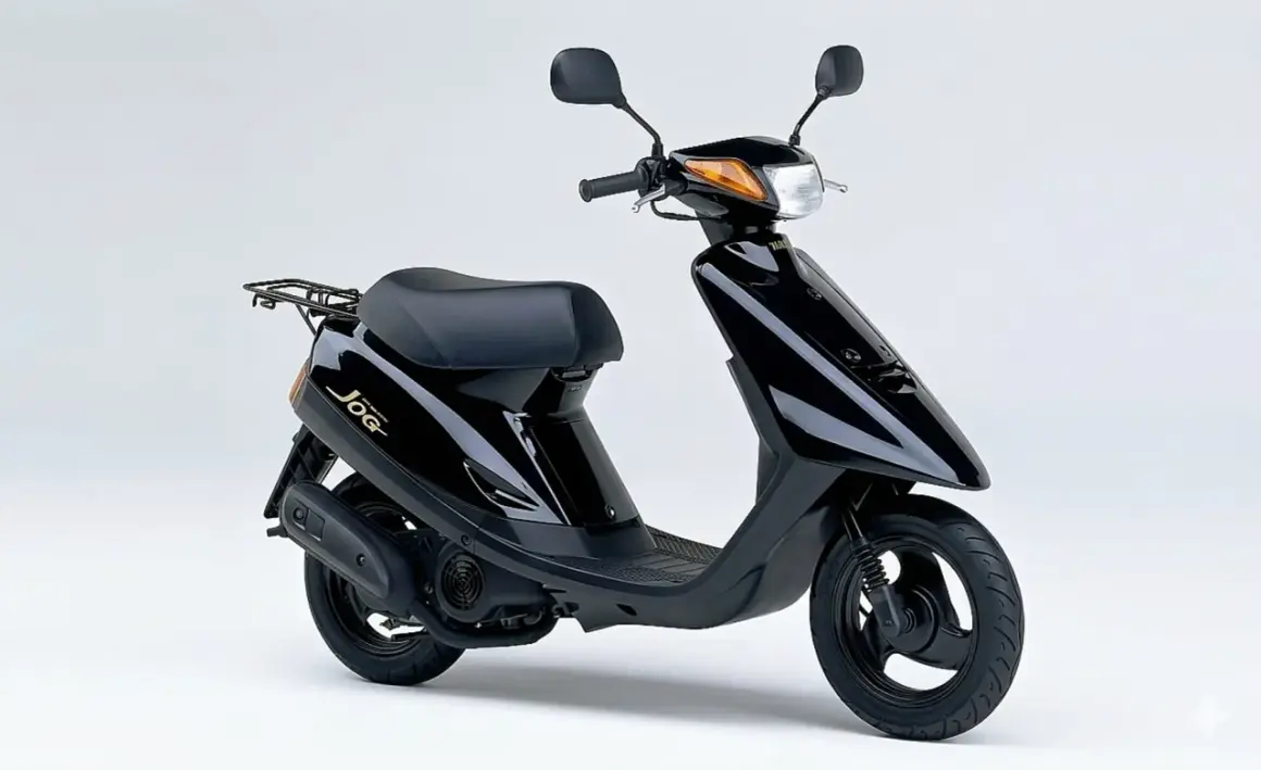 Ciclomotor negro Yamaha Jog, un clásico de los ciclomotores de los 90, con asiento y parrilla trasera.