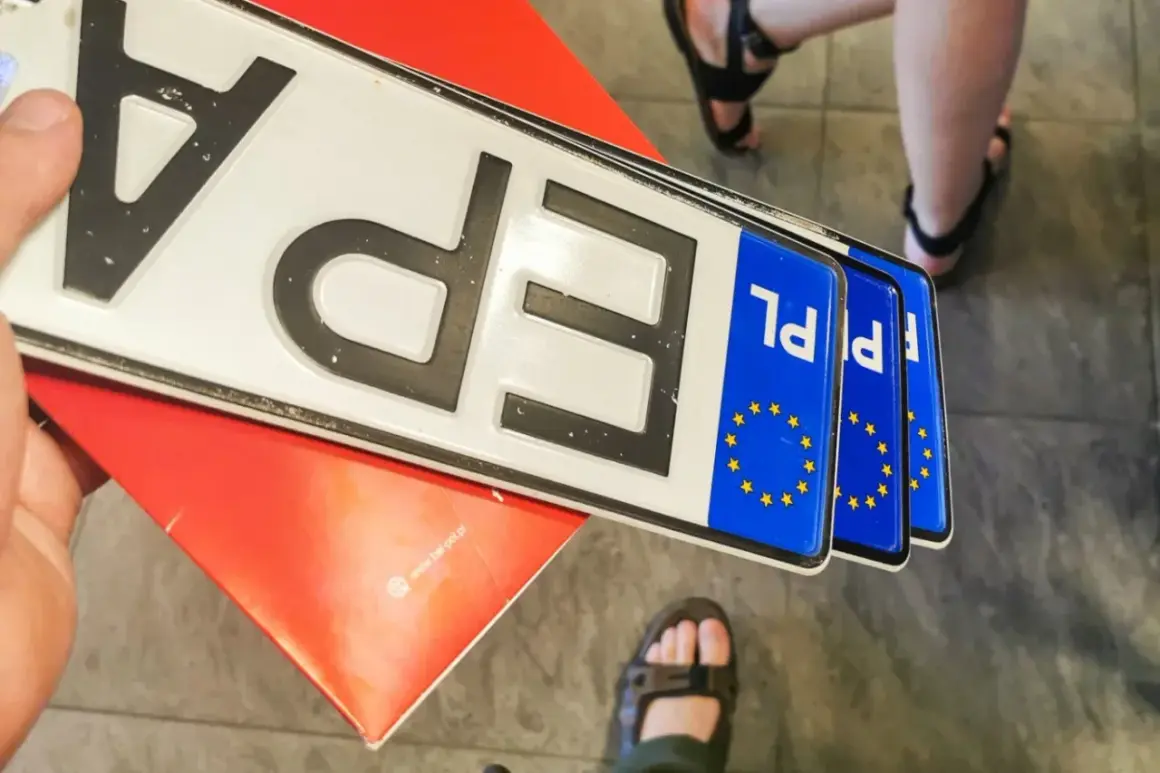 Kilka nowych tablic rejestracyjnych PL leży na czerwonym podkładzie.