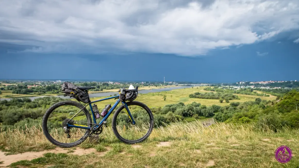 Rower gravelowy z sakwami na tle burzowego nieba nad Wisłą. Przygotowany na wyprawę Wisła 1200.