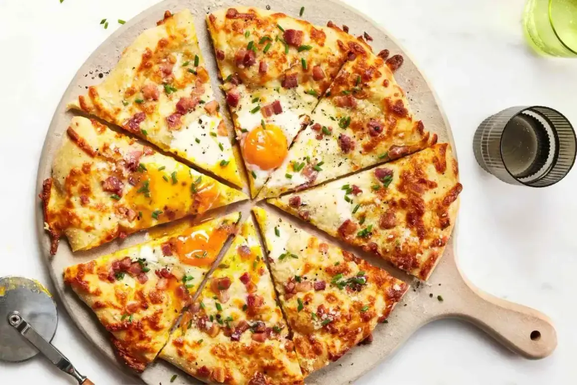 Kawałki pizzy carbonara z jajkiem sadzonym, boczkiem i szczypiorkiem, ułożone na desce.