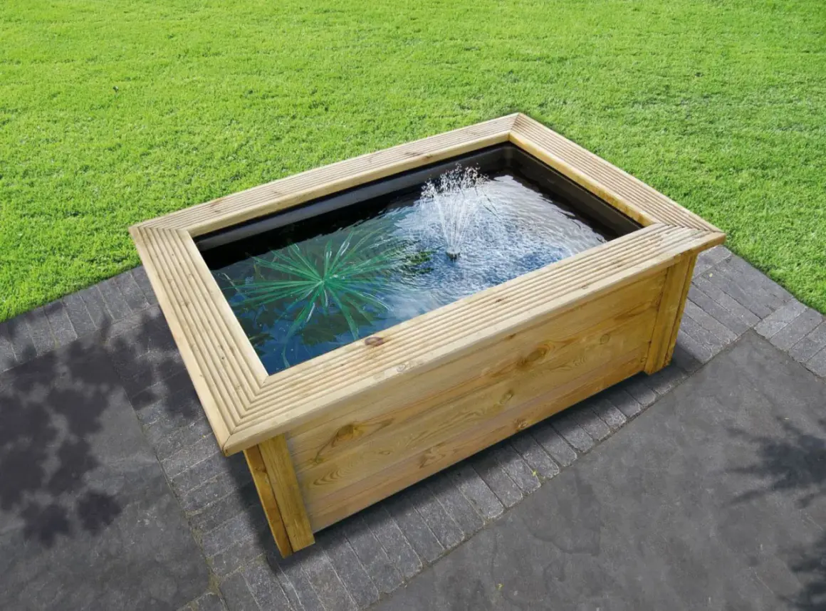 Un bassin préformé hors sol en bois avec une fontaine et une plante aquatique, prêt à être installé dans un jardin.