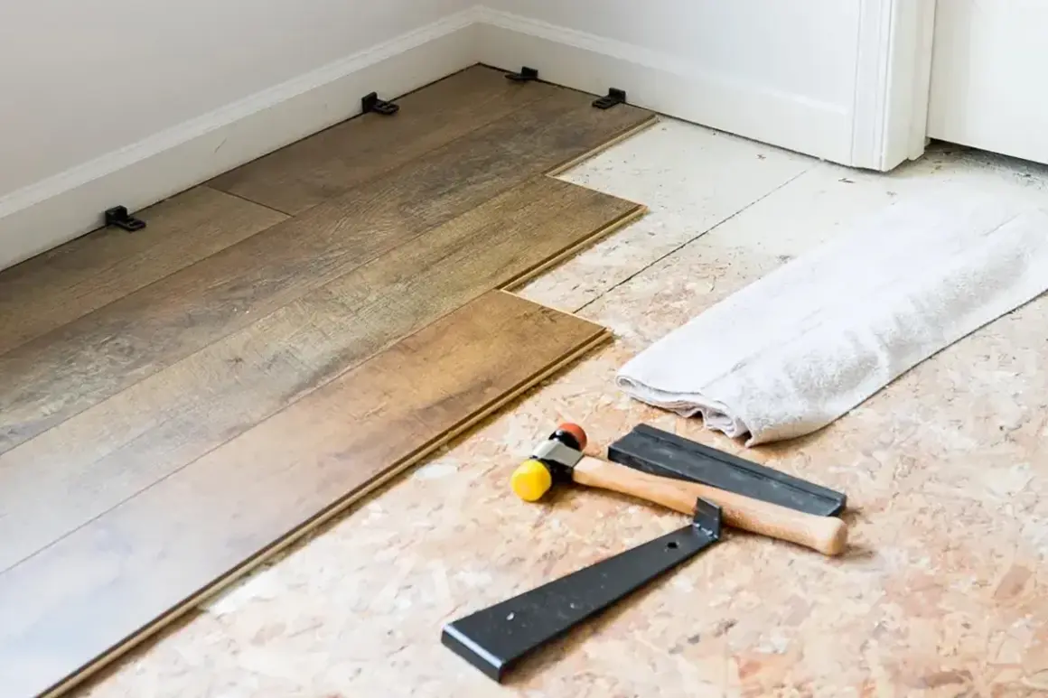 Laying LVP flooring parallel to the longest wall is a common practice. Tools like a rubber mallet and pry bar are ready for installation.
