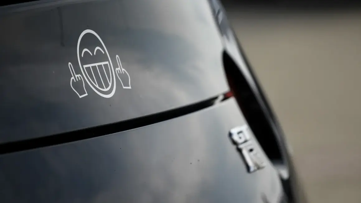 Lachendes Smiley-Gesicht mit Mittelfingern als Aufkleber am Auto. Welche Aufkleber am Auto sind erlaubt?