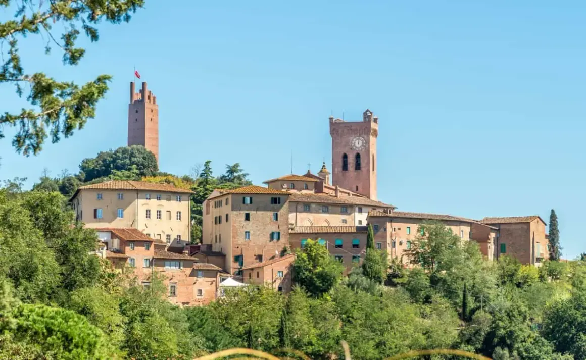 Borgo medievale di San Miniato con torri imponenti e case in pietra, immerso nel verde della campagna toscana.