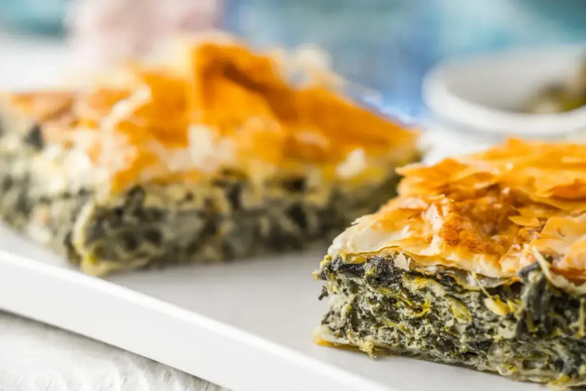 Chrupiąca spanakopita z warstw ciasta filo i zielonym nadzieniem ze szpinaku i sera.