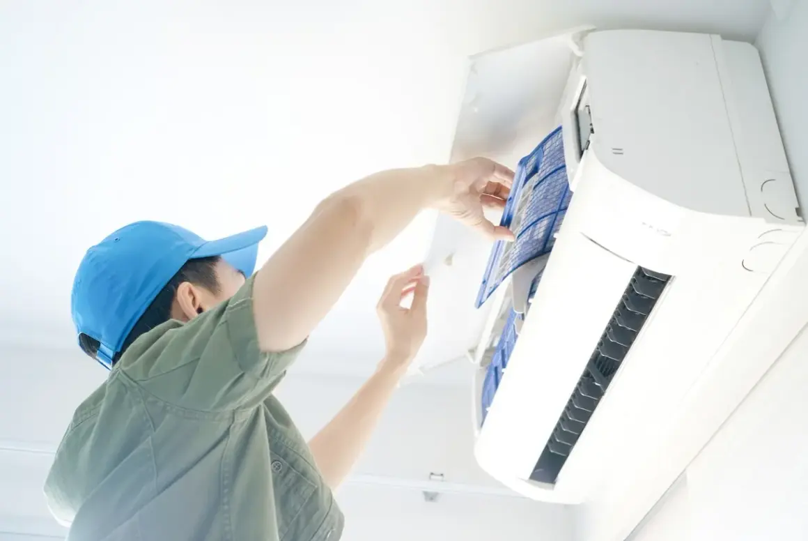 Un technicien nettoie le filtre d'une climatisation, une obligation pour le bailleur afin d'assurer le confort et la qualité de l'air.