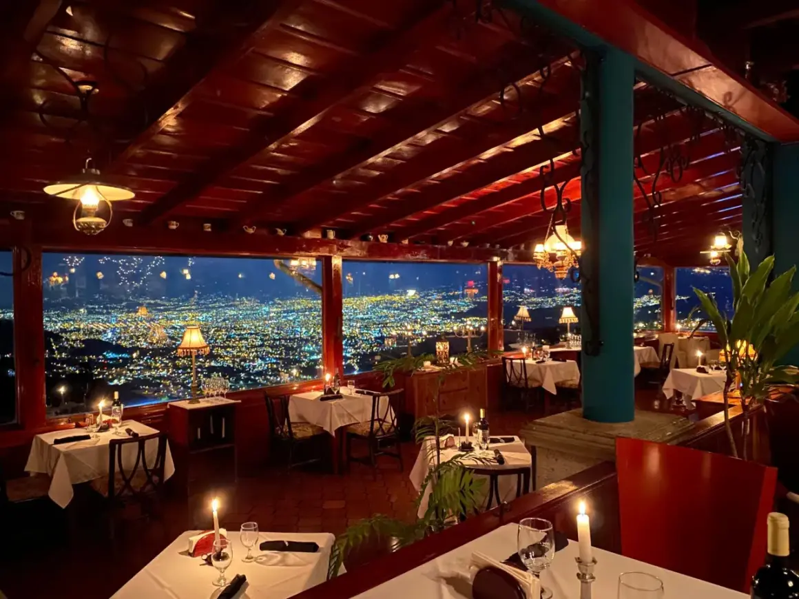 Mesas puestas con velas y vistas a la ciudad iluminada. Un lugar perfecto para saber donde cenar en San José.