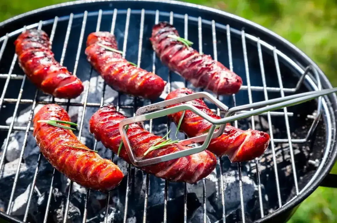 A pyszna kiełbasa na grila, rumiana i soczysta, z gałązkami rozmarynu, pieczona na węglu.