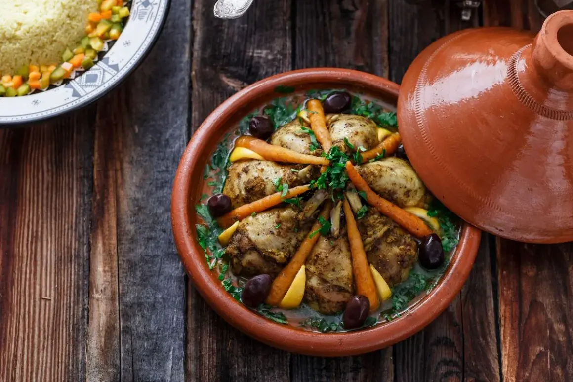 Ein Hähnchen-Tajine mit Karotten, Oliven und Zitrone, serviert in einem traditionellen Tontopf.