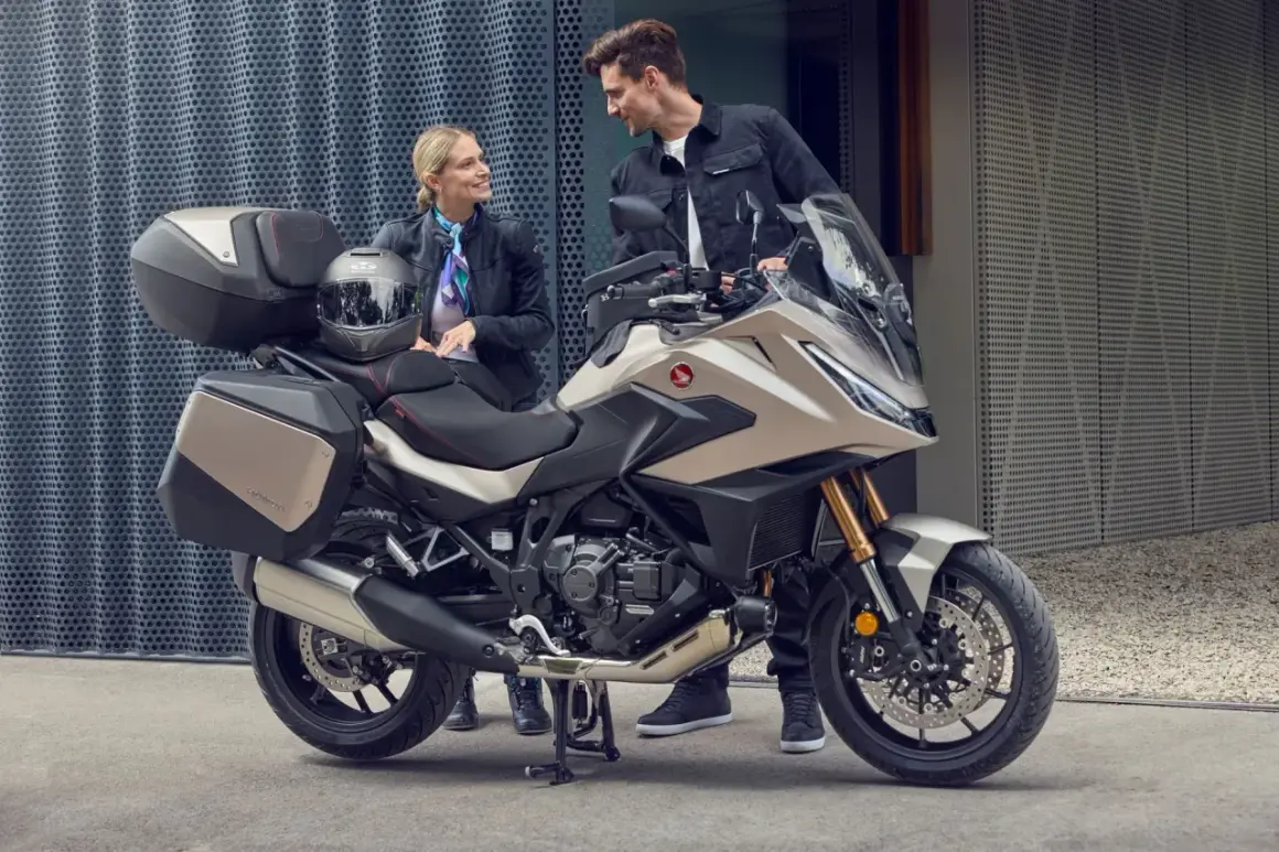 Pareja sonriente junto a una Honda NT 1100, lista para viajar. Opiniones positivas sobre su comodidad y diseño.