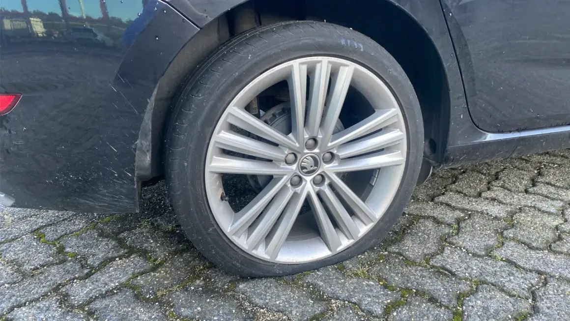 Een lekke band op de racefiets van de auto. De band is plat en de velg rust op de stenen ondergrond.