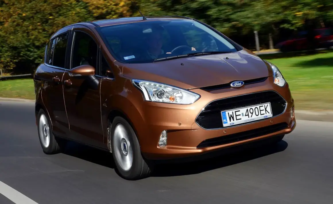 Brązowy Ford B-Max jedzie po drodze, za nim drzewa w jesiennych barwach.