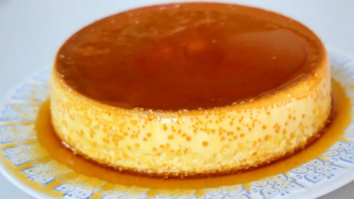 Delicioso flan de queso Philadelphia con caramelo líquido, servido en un plato blanco con diseño azul.