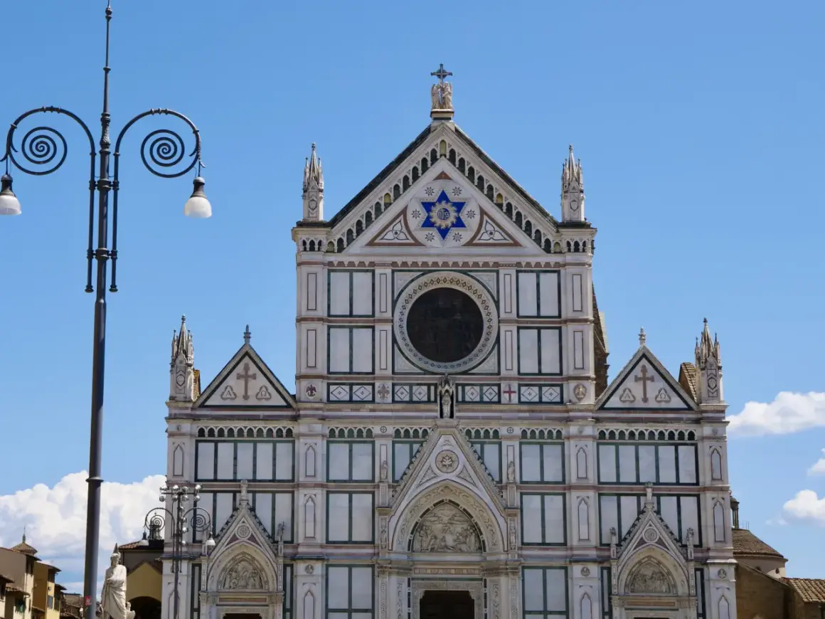 Fasada katedry Santa Maria del Fiore we Florencji, ozdobiona mozaikami i rzeźbami, lśni w słońcu.
