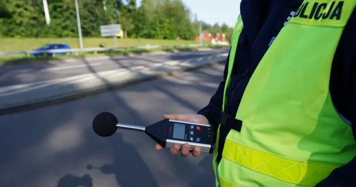 Policjant mierzy poziom hałasu. Sprawdza, ile decybeli może mieć auto, by nie przekraczać norm.