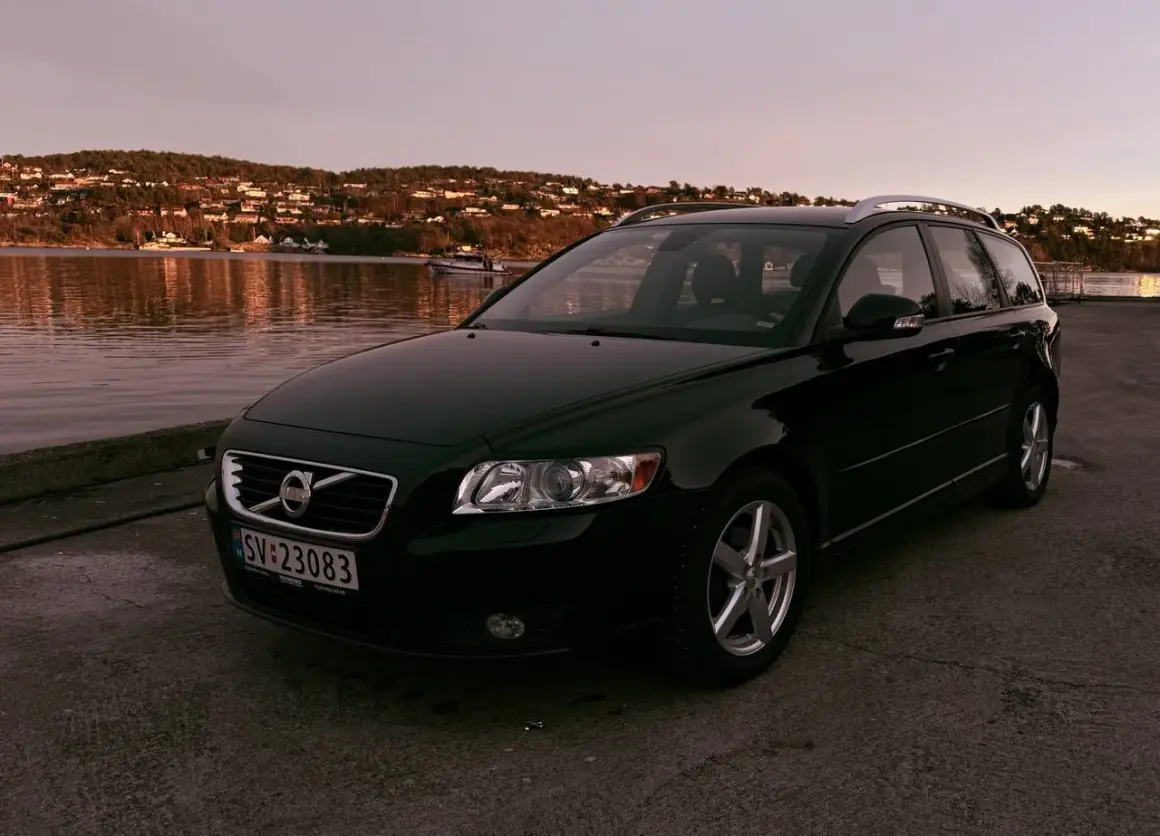 Svart Volvo V50 vid vattnet i solnedgången. Denna bilmodell är känd för sina pålitliga volvo v50 motorer.