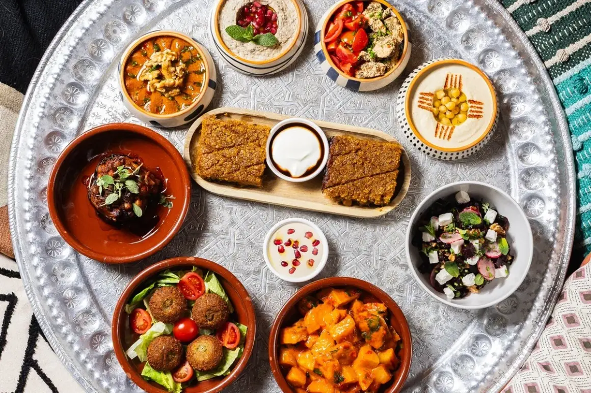 Un vassoio con diverse pietanze mediorientali, perfetto per scoprire dove mangiare a Milano. Hummus, falafel, insalate e spezzatini invitano a un viaggio di sapori.