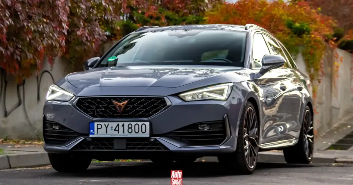 Szary Cupra kombi z jesiennymi liśćmi w tle.