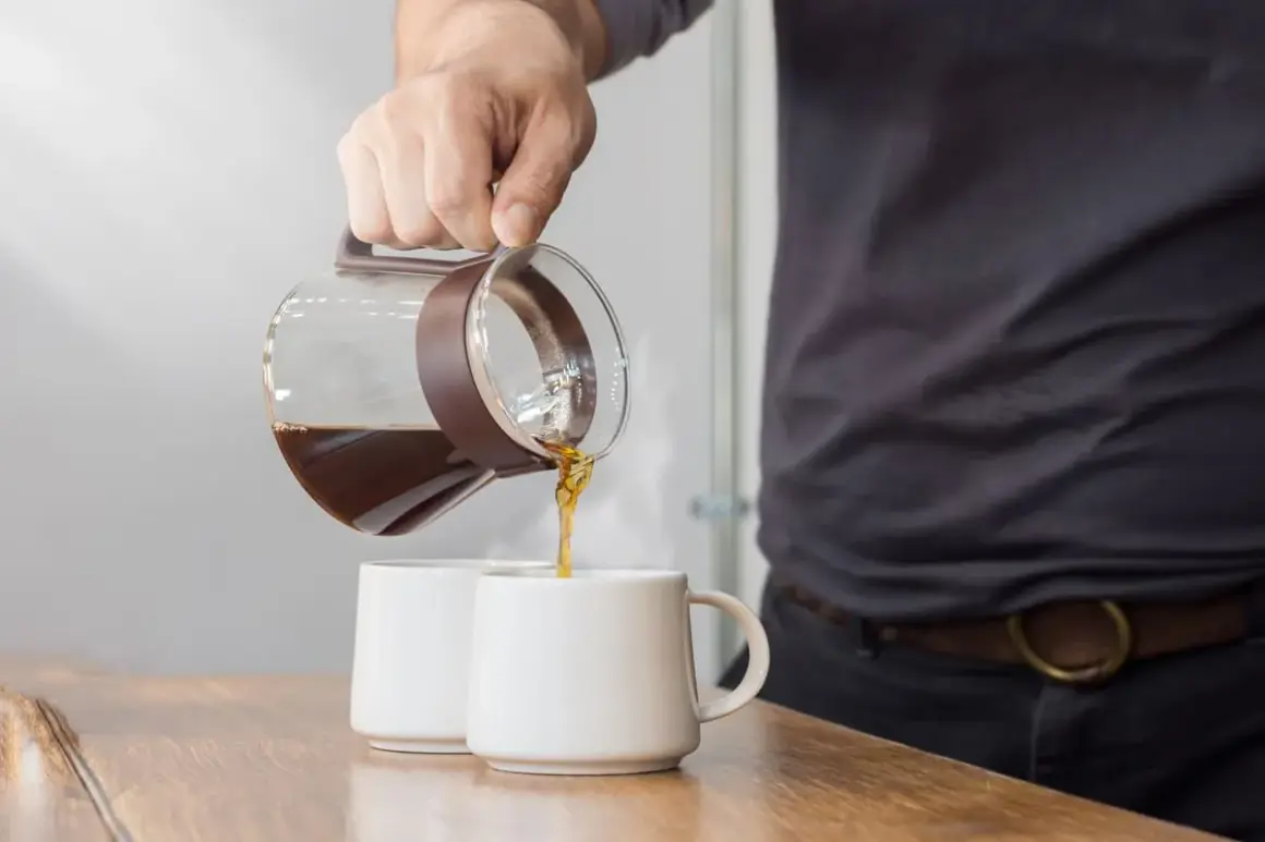 Versando caffè da una caraffa in due tazze. La scelta del caffè giusto è fondamentale per una macchina caffè americano.