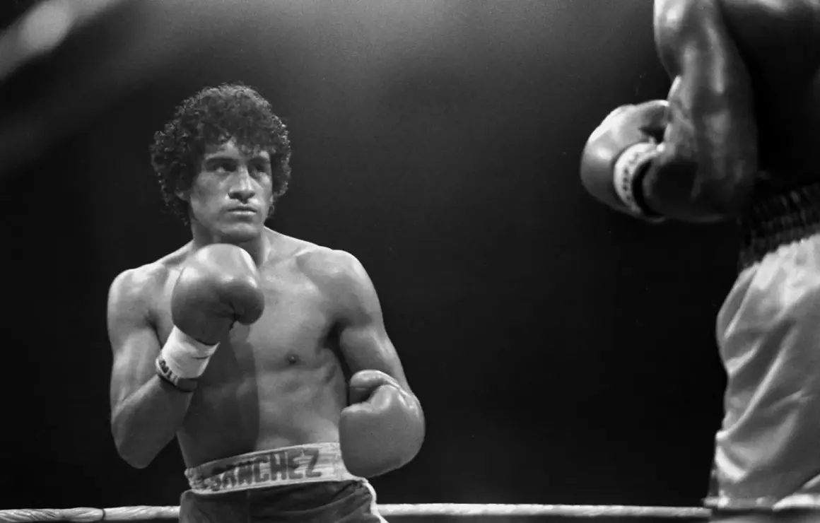Salvador Sanchez, a legendary boxer, stands ready in the ring, his reach evident as he faces an opponent.
