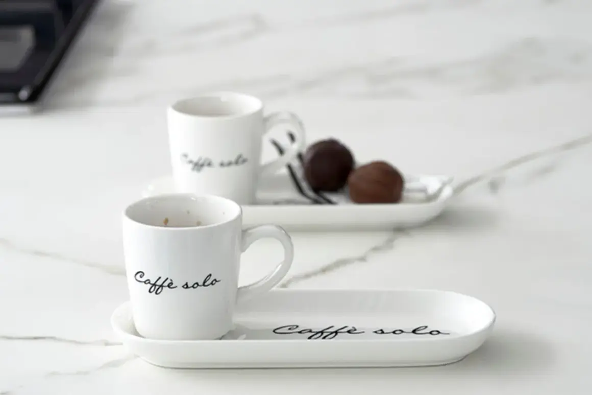 Eleganckie filiżanki z napisem "Caffè solo" i czekoladki na talerzykach. Idealny sposób, jak podawać kawę gościom.